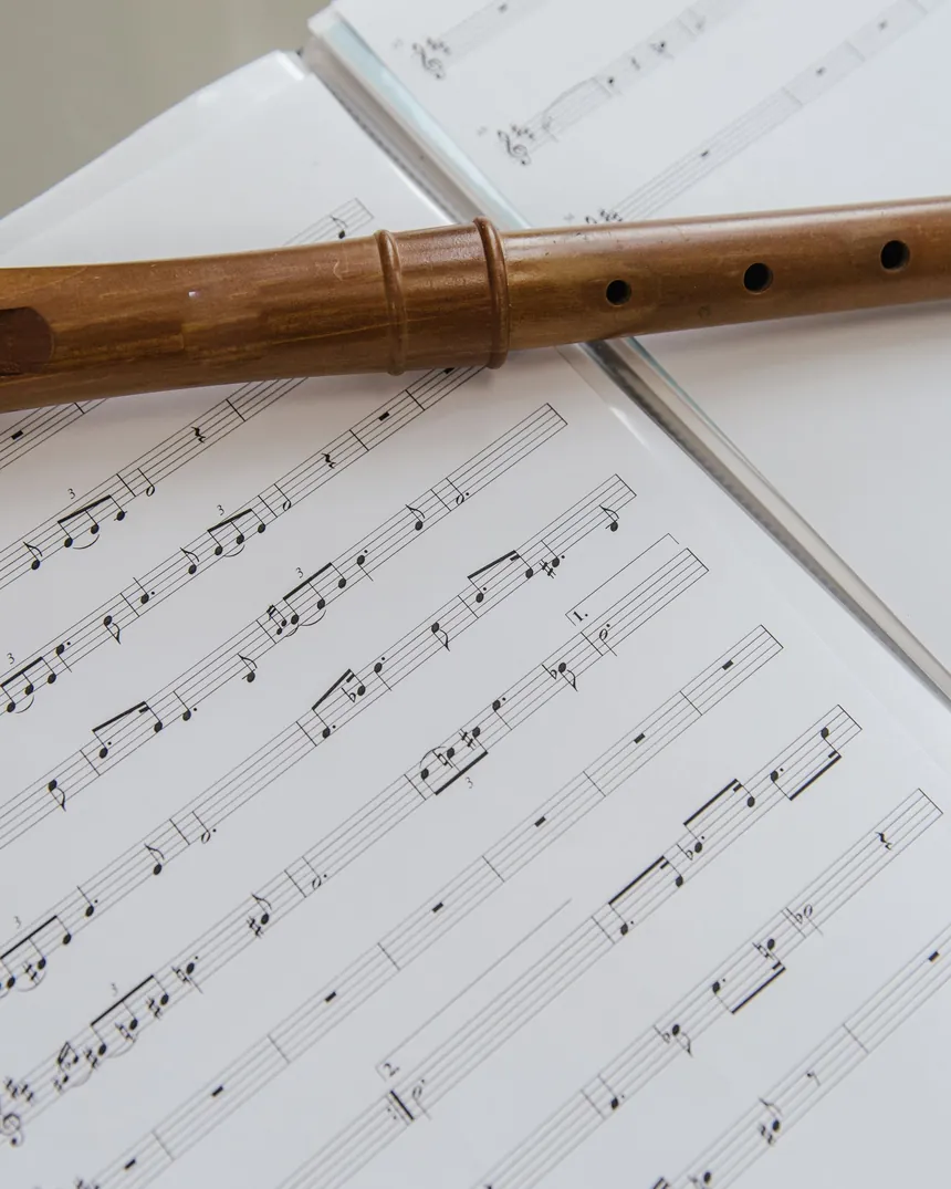 Flauta de madera apoyada sobre una partitura, con el cuerpo y los agujeros vistos de cerca